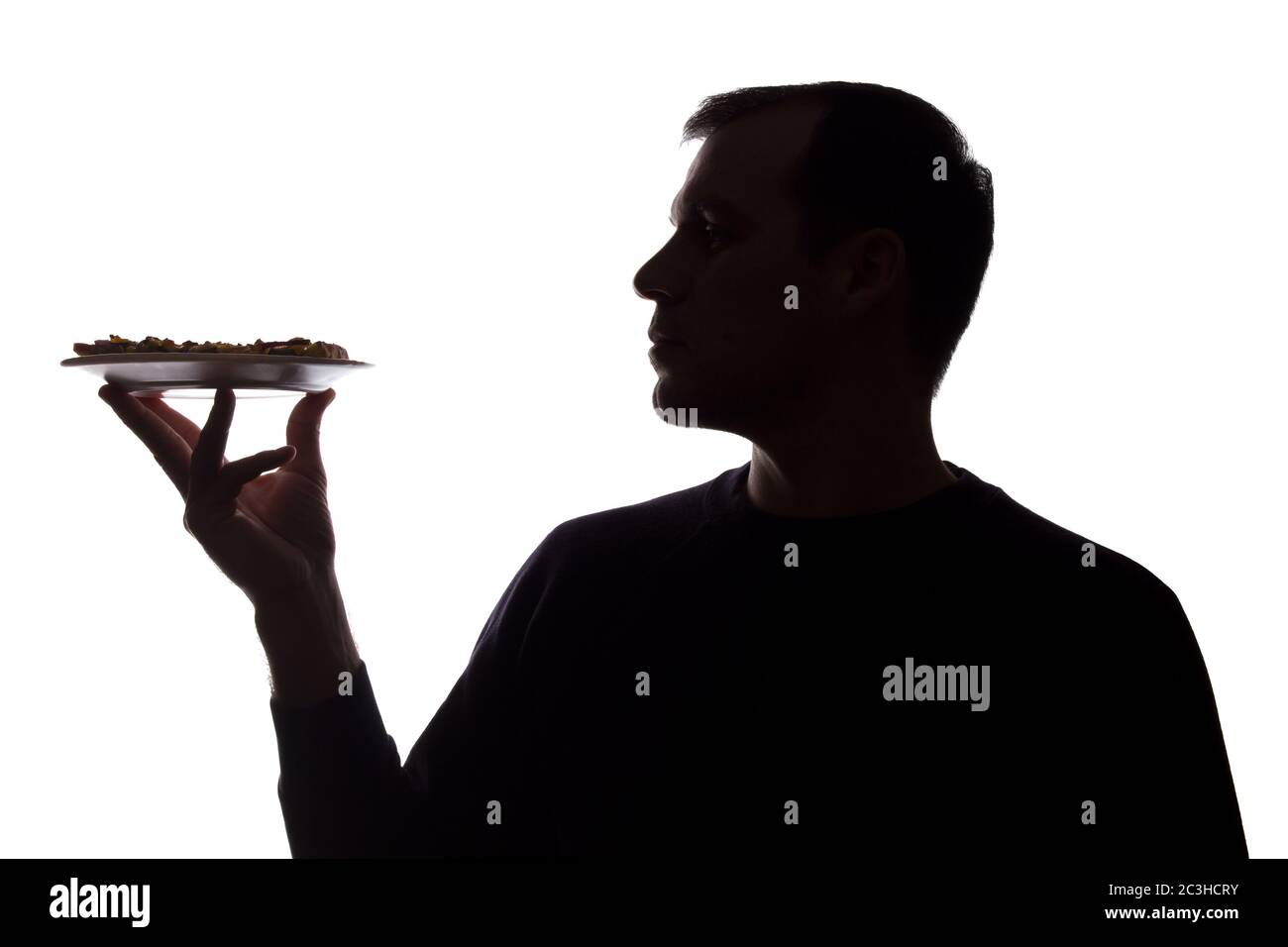 Porträt eines jungen Mannes mit Pizza auf einem Teller in der Hand, unrasiert, Seitenansicht - dunkel isolierte Silhouette Stockfoto