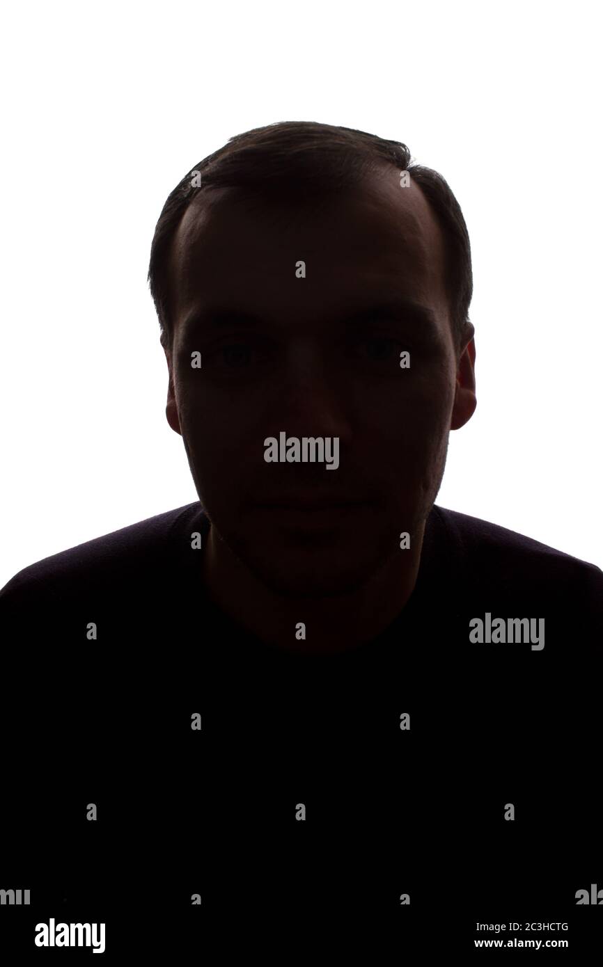 Porträt eines jungen Mannes, unrasiert, Vorderansicht - dunkel isoliert Silhouette Stockfoto
