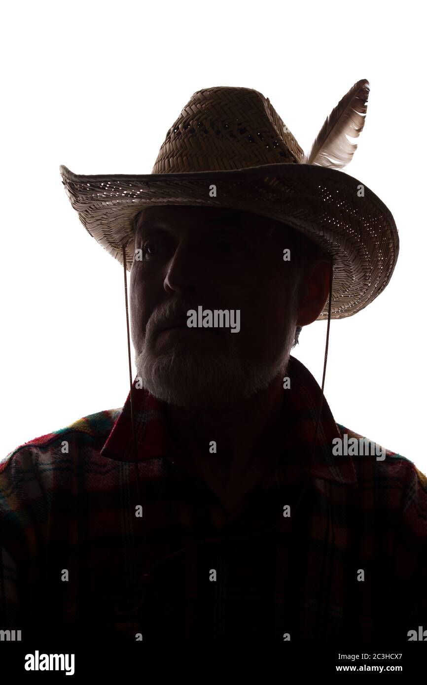 Porträt eines alten Mannes, in einem Cowboy Hut mit Feder, mit Bart, Vorderansicht - dunkel isoliert Silhouette Stockfoto