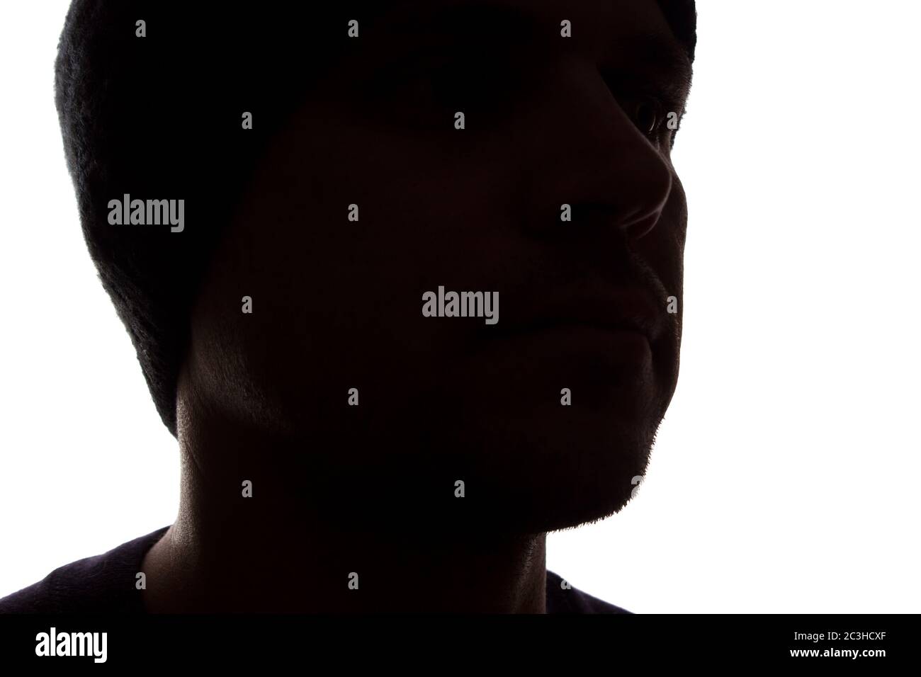 Porträt eines jungen Mannes, unrasiert, Seitenansicht in Mütze - dunkel isolierte Silhouette Stockfoto