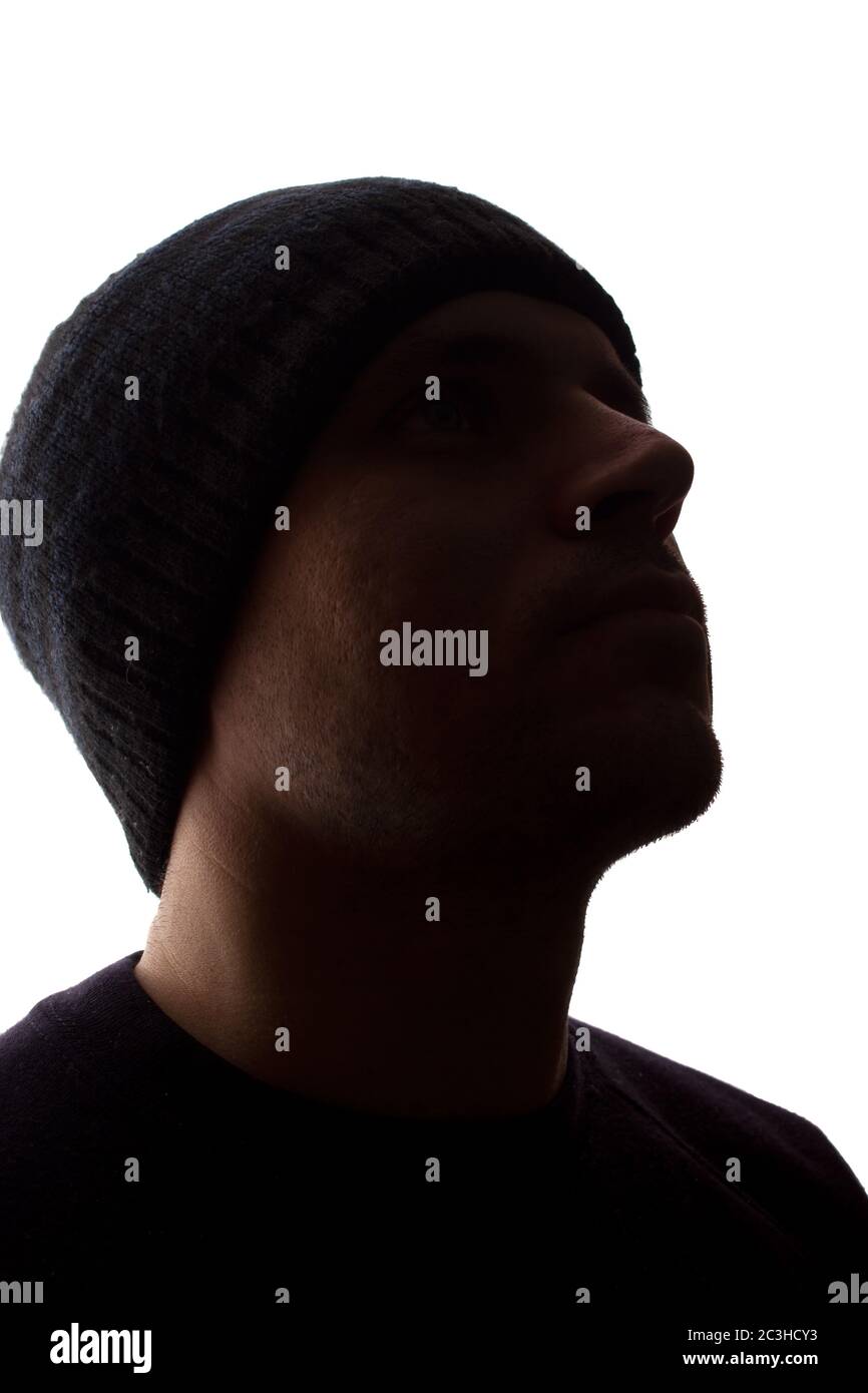 Porträt eines jungen Mannes, unrasiert, Seitenansicht in Mütze - dunkel isolierte Silhouette Stockfoto