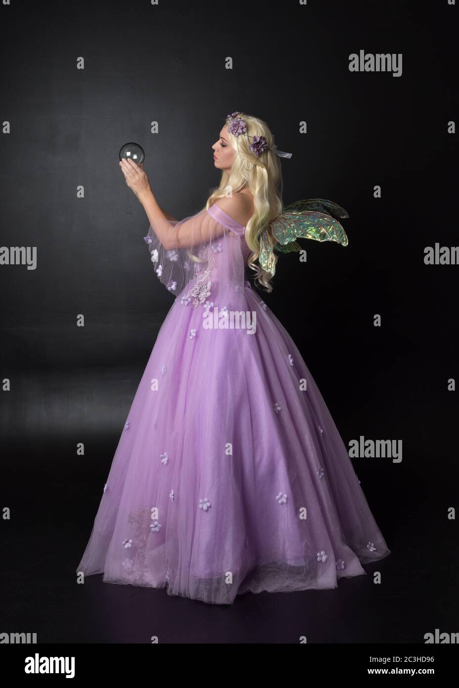 Portrait einer schönen blonden Fee trägt lila Fantasy-Kleid mit Flügeln. In voller Länge stehende Pose, isoliert vor einem Studio-Hintergrund. Stockfoto