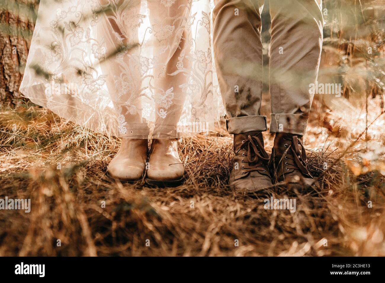 Nahaufnahme eines Paares in alten Stiefeln in einem Feld mit getrocknetem Gras während des Tages Stockfoto