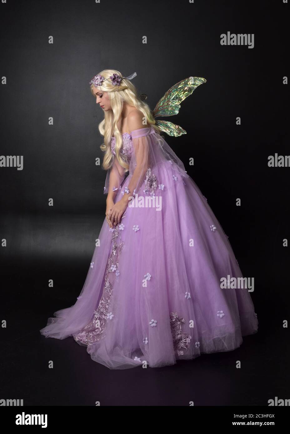 Portrait einer schönen blonden Fee trägt lila Fantasy-Kleid mit Flügeln. In voller Länge stehende Pose, isoliert vor einem Studio-Hintergrund. Stockfoto