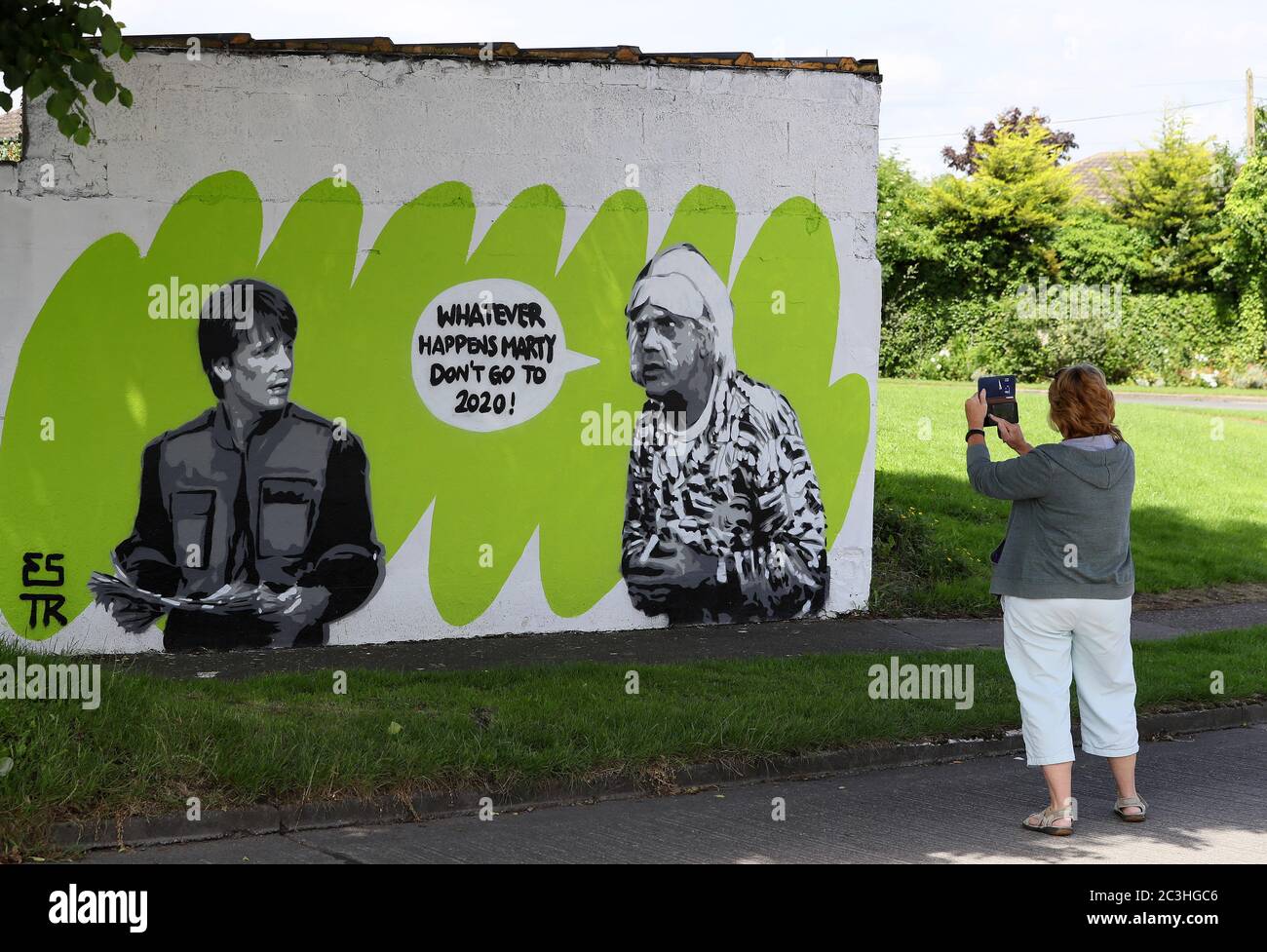 Eine Frau hält an, um das Wandbild der irischen Künstlerin Emmalene Blake mit den Figuren Marty McFly und Doc Brown aus dem Kult-80er-Film "Zurück in die Zukunft" in South Dublin zu fotografieren. Dies ist das neueste Coronavirus-Wandbild des Künstlers in Dublin während der Pandemie. Weitere Künstler waren Dua Lipa, Robyn und Cardi B. Stockfoto