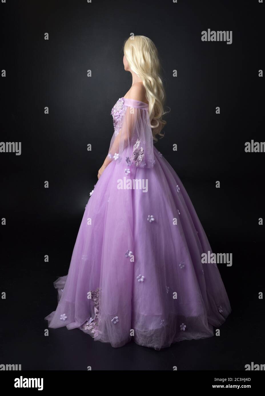 Portrait einer schönen Blondine tragen lila floralen, Fantasy-Kleid. In voller Länge stehende Pose, isoliert vor einem Studio-Hintergrund. Stockfoto