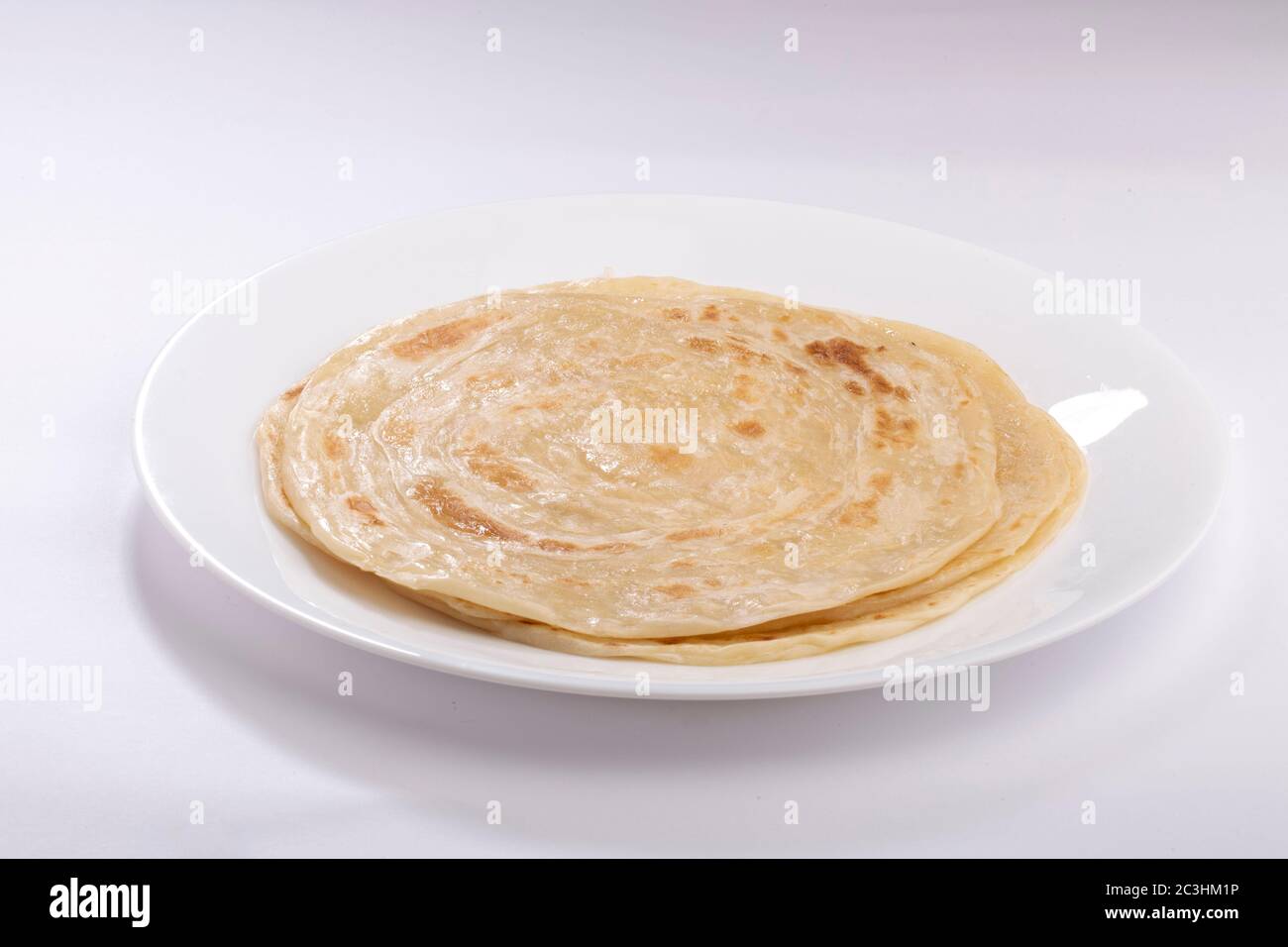 Hausgemachtes Kerala Parotta/ Porotta /Paratta /geschichtetes Fladenbrot mit maida oder raffiniertem Mehl oder Allzweckmehl, das wunderschön auf einem weißen Teller angeordnet ist Stockfoto