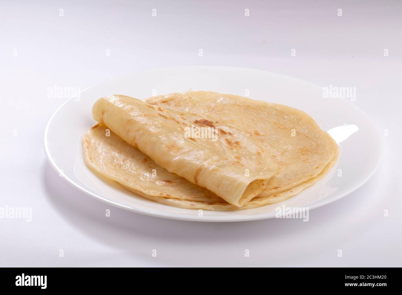 Hausgemachtes Kerala Parotta/ Porotta /Paratta /geschichtetes Fladenbrot mit maida oder raffiniertem Mehl oder Allzweckmehl, das wunderschön auf einem weißen Teller angeordnet ist Stockfoto