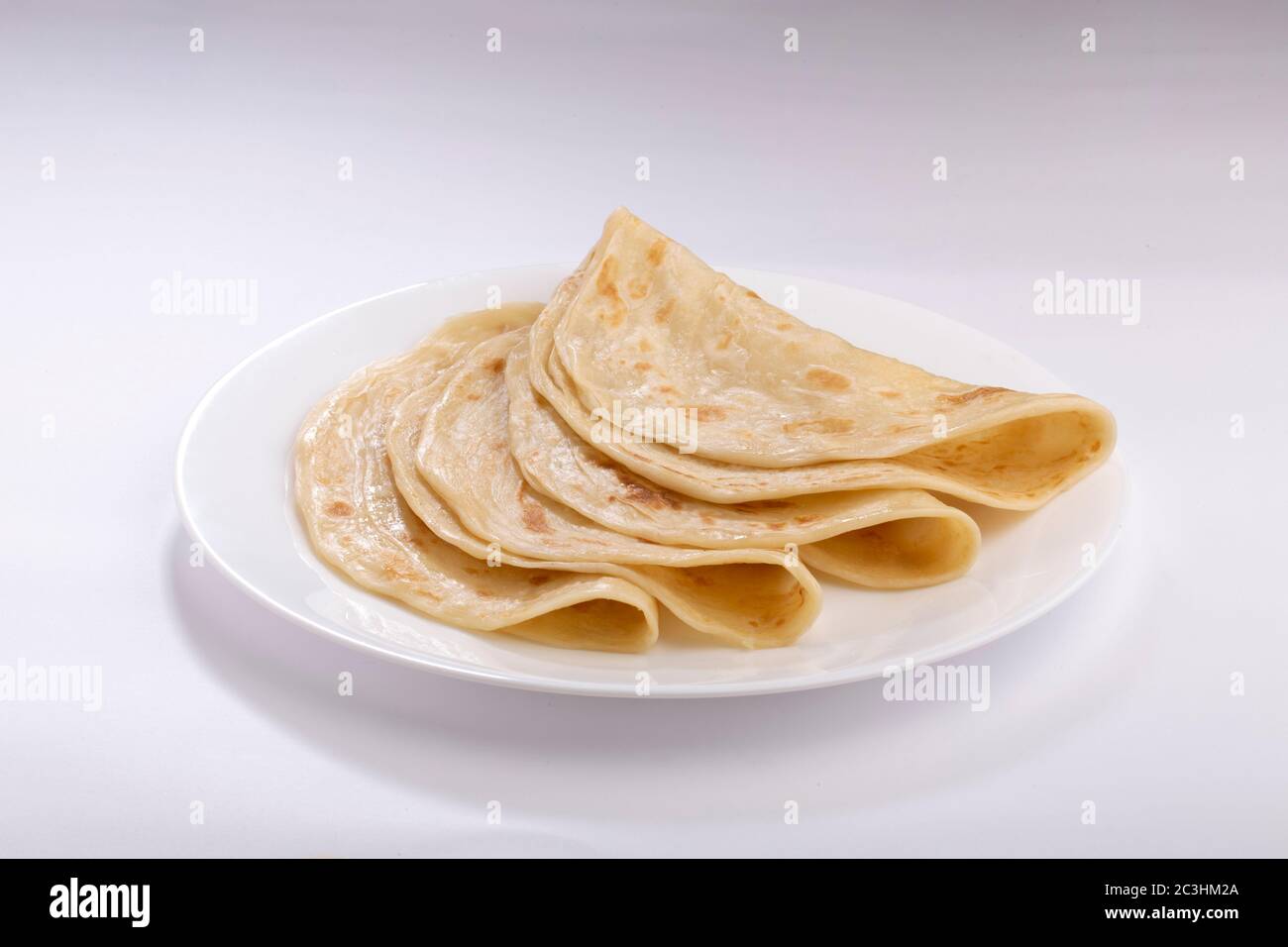 Hausgemachtes Kerala Parotta/ Porotta /Paratta /geschichtetes Fladenbrot mit maida oder raffiniertem Mehl oder Allzweckmehl, das wunderschön auf einem weißen Teller angeordnet ist Stockfoto