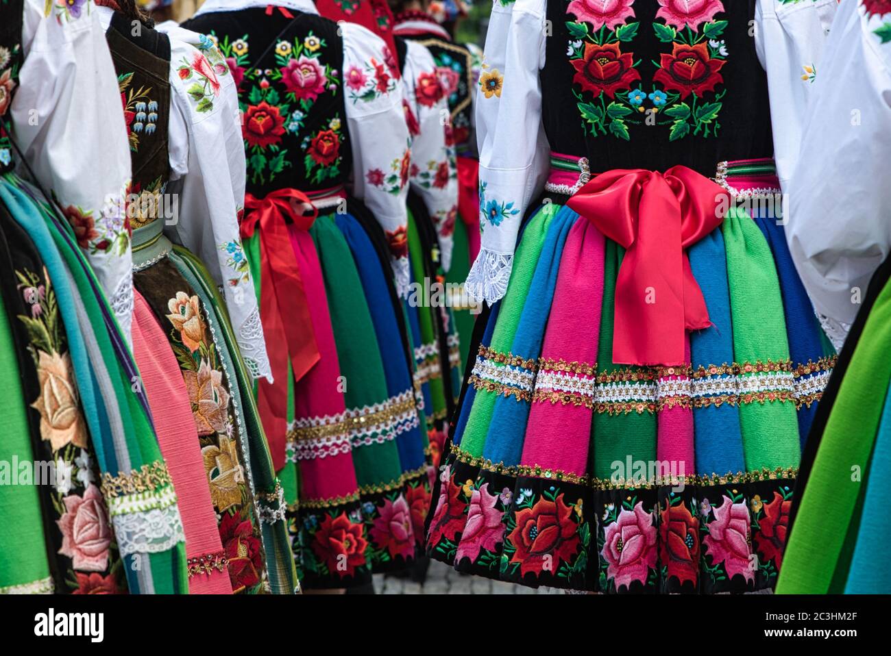Mädchen in polnischen nationalen Volkstrachten aus der Region Lowicz während der jährlichen Fronleichnamsprozession gekleidet. Traditionelle bunt gestreifte Volksröcke Stockfoto