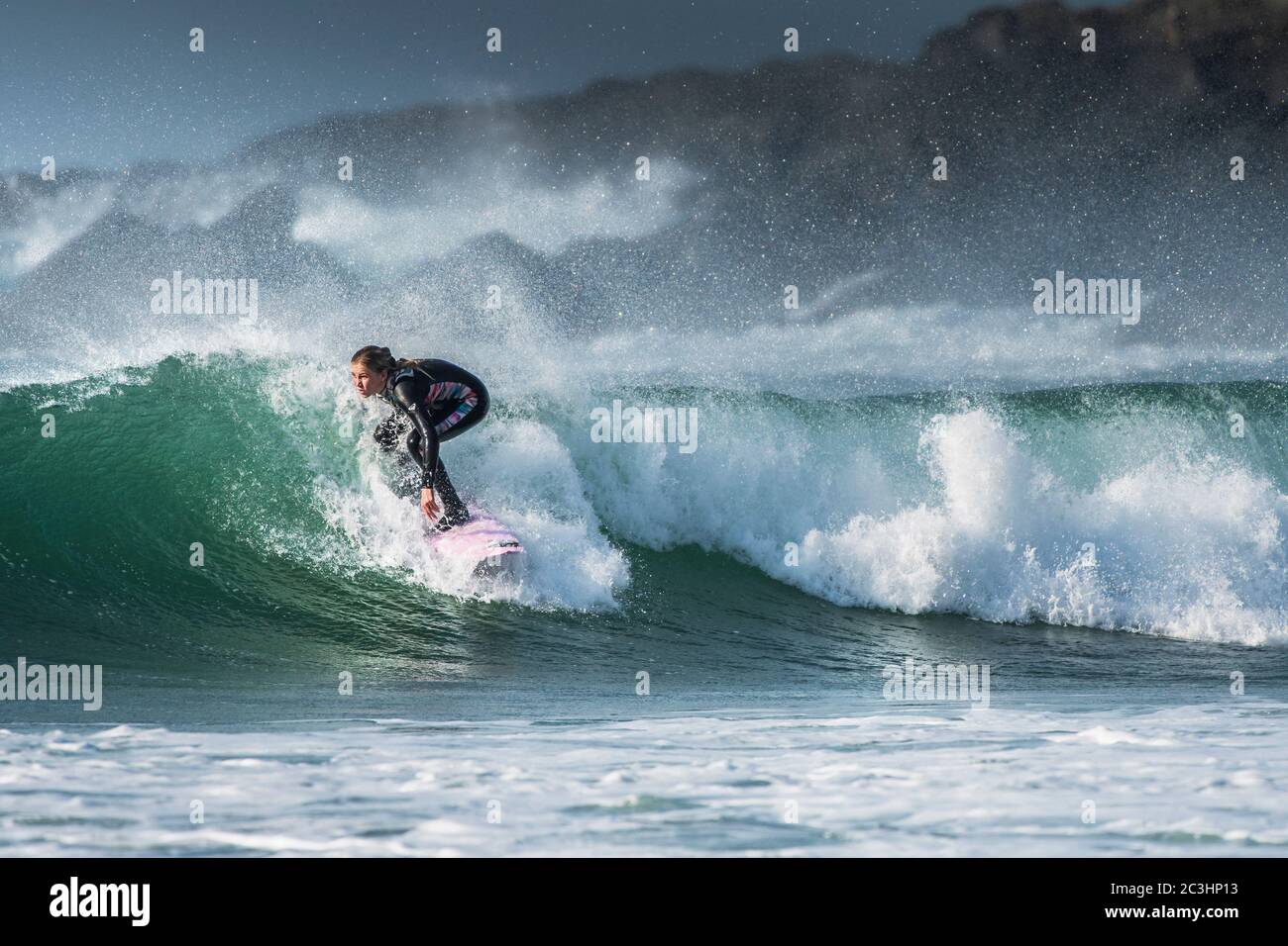 Spektakuläre surfen Aktion als eine junge weibliche Surfer reitet eine Welle an Fistral in Newquay in Cornwall. Stockfoto