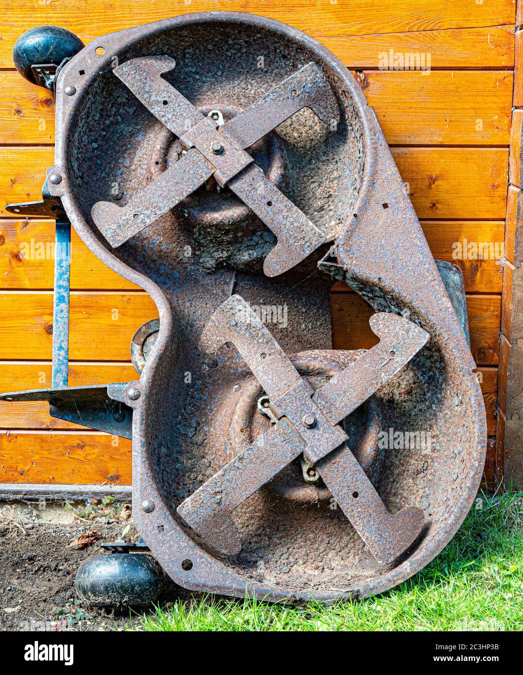 Ein rostiger Stahl Metall, zwei Mähdeck, mit vier Klingen, von einer Fahrt auf Mäher, stehend aufrecht draußen gegen eine Holzkabine. Stockfoto