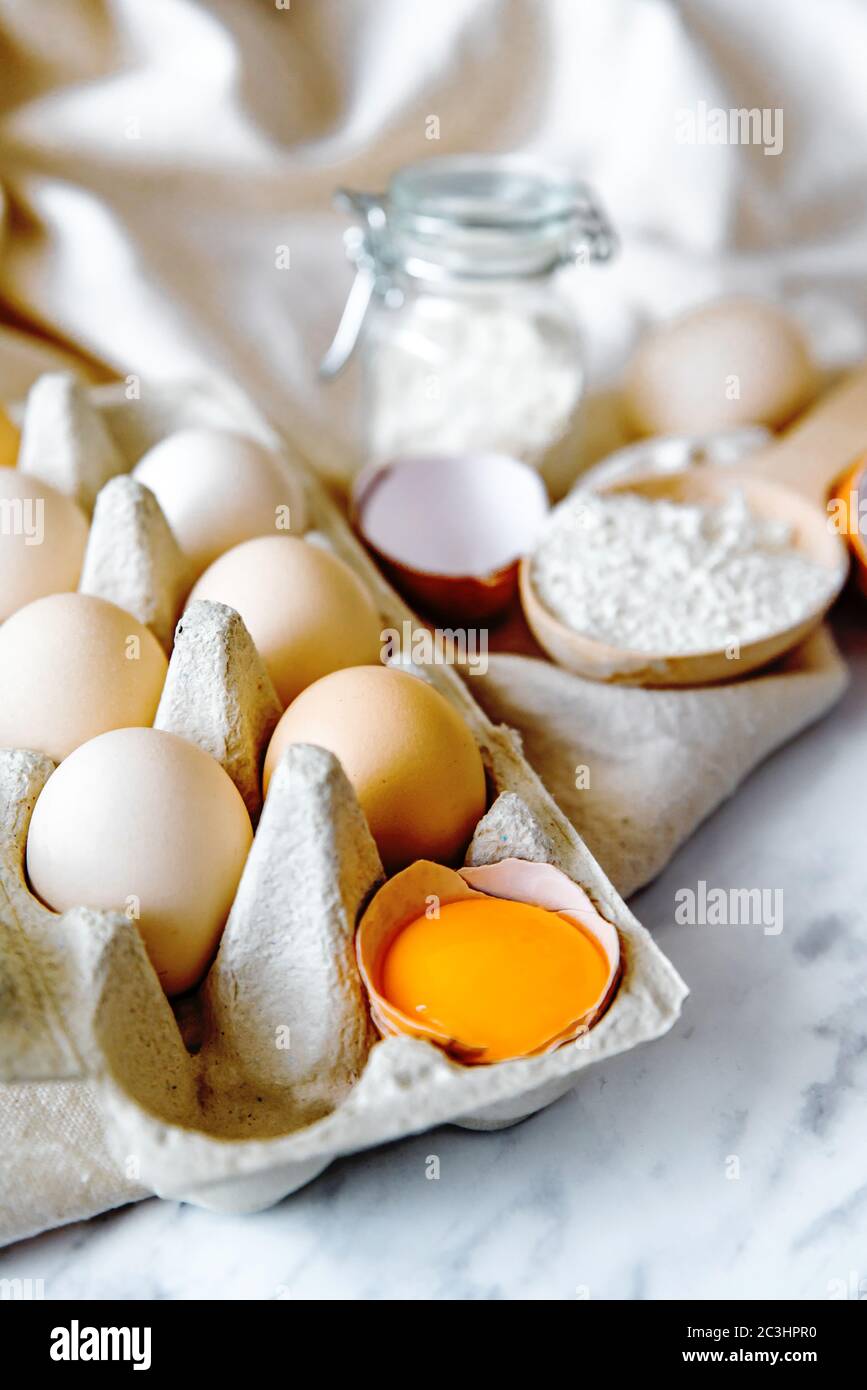 Backzutaten mit Eiern, Weizenmehl, Eigelb für Gebäck. Kuchen, Pasta oder Teig Rezept Zutaten. Draufsicht auf dem Tisch Stockfoto