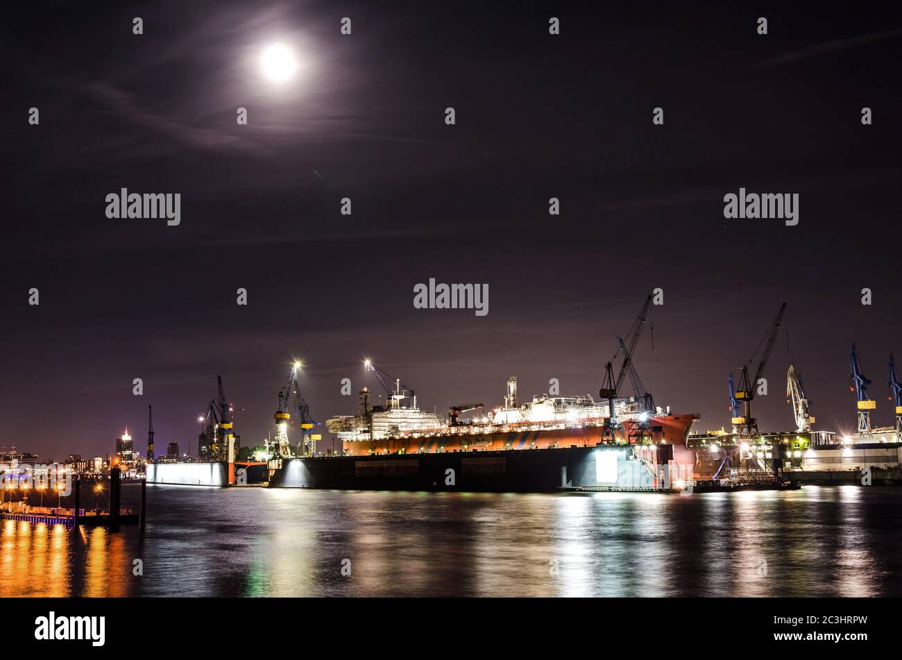 Nachtaufnahme von Dock mit großem Containerschiff an der Elbe in Hamburg Stockfoto