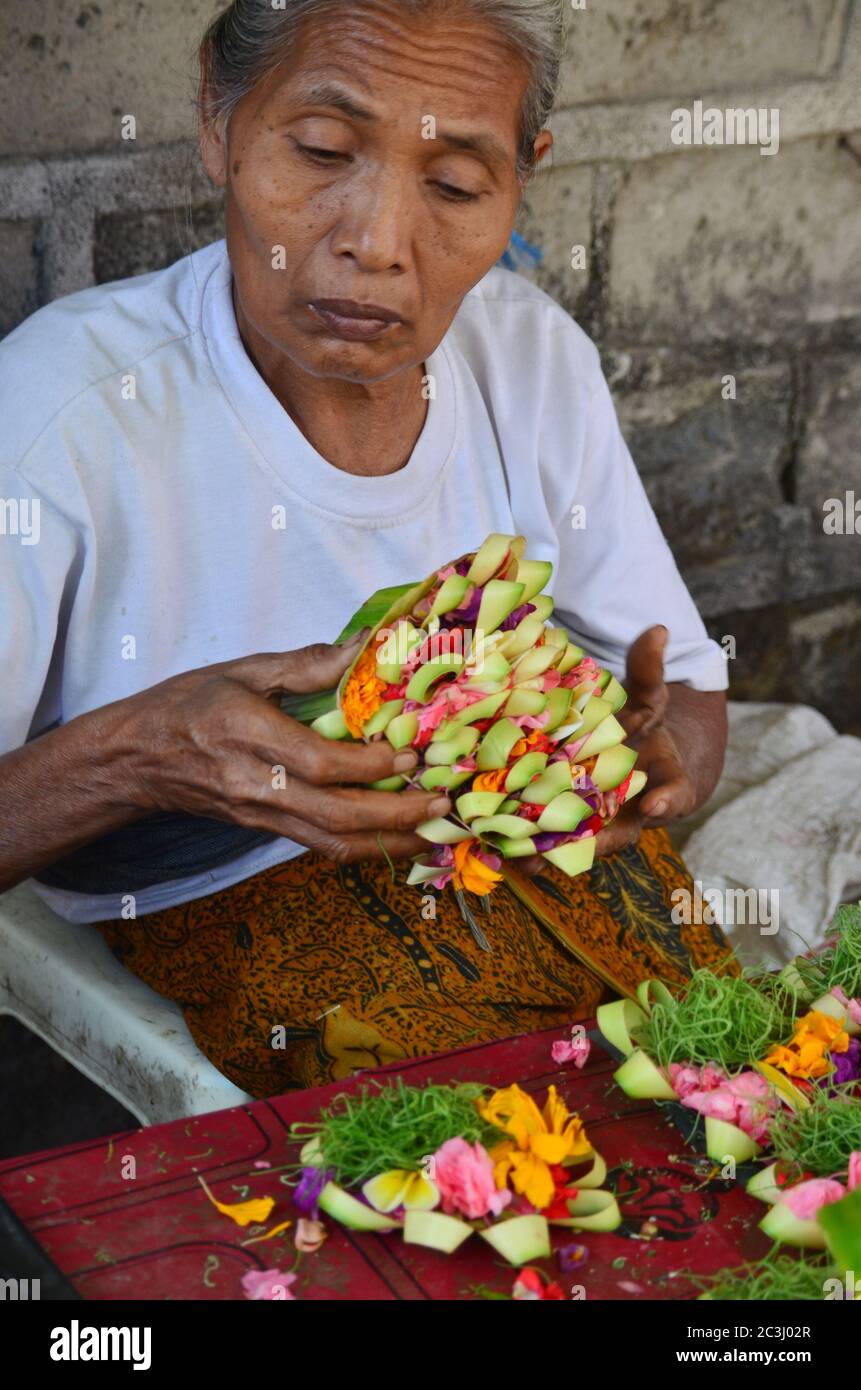 Balinesin Frau, die die Opferblume mit frischen tropischen Blumen macht. Canang Sari ist ein Symbol der Dankbarkeit für den balinesischen Hinduismus. Stockfoto