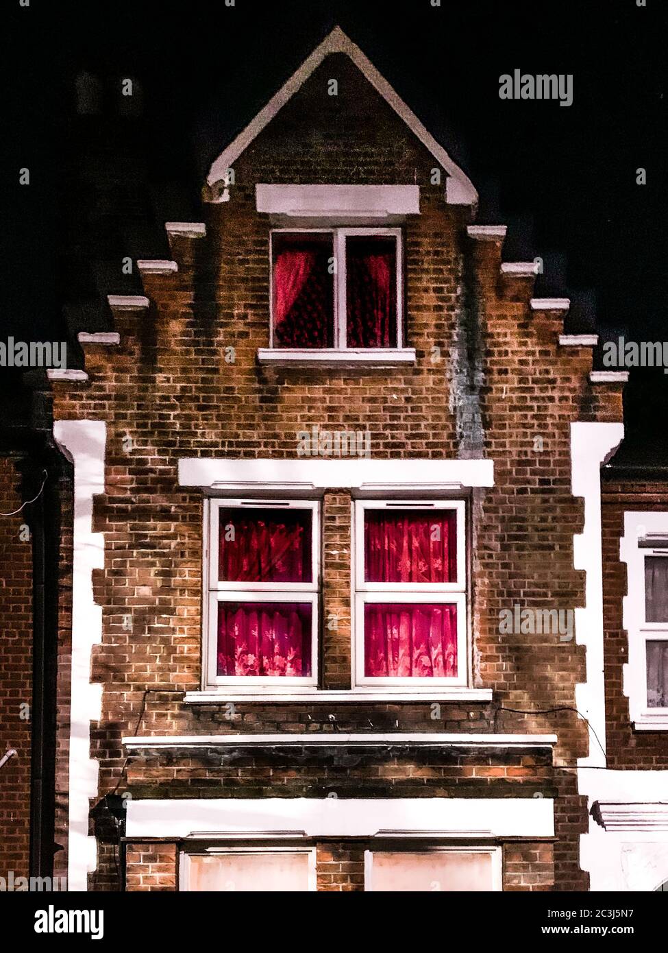 Vertikale Aufnahme eines alten Backsteinhauses mit weißen Fenstern Stockfoto