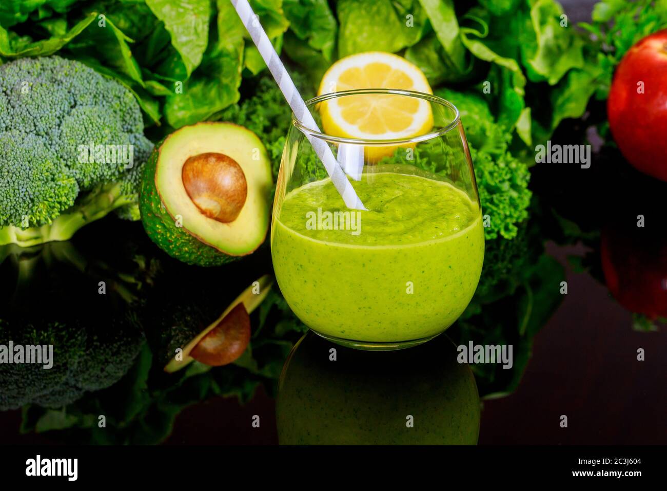 Gemüse gesunder Smoothie im Glas mit Stroh und Zutaten auf schwarzem Tisch. Stockfoto