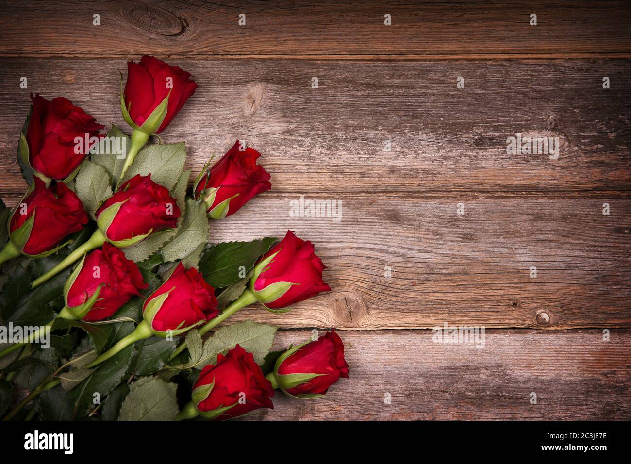 Rote Rosen über altem Holzhintergrund mit gewollter Vignette. Ideales Bild  für Geburtstag, Valentinstag und Feier Karten Stockfotografie - Alamy