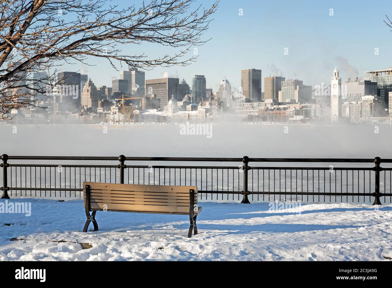 Blick über den St. Lawrence River bis ins Zentrum von Montreal. Winter mit Schnee auf dem Boden und Nebel steigt aus dem gefrorenen Wasser. Stockfoto