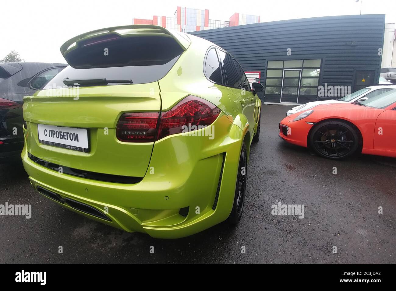 Moskau, Russland - 05. Mai 2019: Limette Green getunten Porsche Cayenne mit breiten Kit von Hamman, modifizierte Haube, Pad auf der fünften Tür. In der Nähe ist ein roter Porsche 911 Rückseite Ansicht Stockfoto