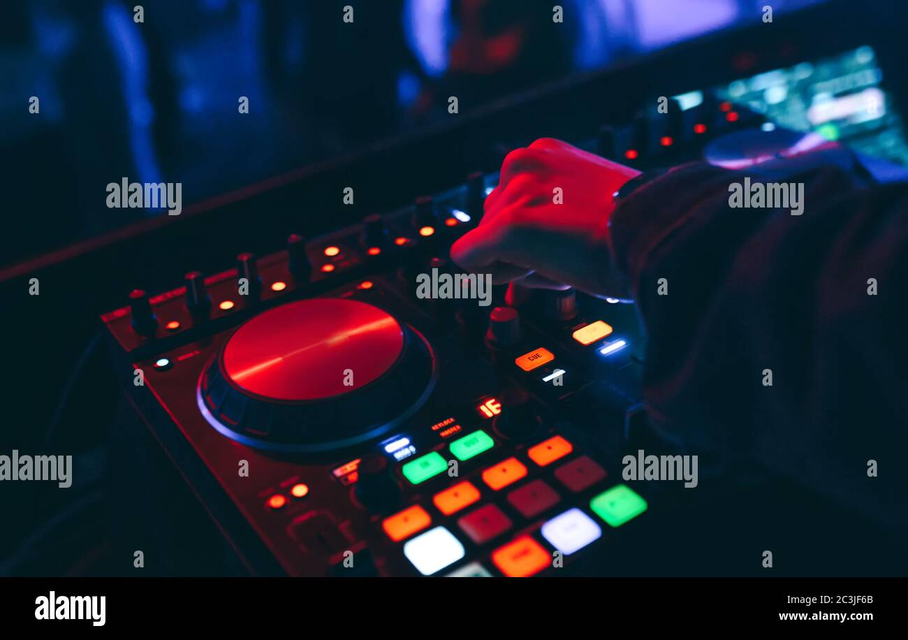 Produzent DJ Mixer in einem Nachtclub mit glühenden spielt musikalische Rave Dubstep Elektronische Trance Komposition mit modernen Midi-Controller-Gerät in Nightglu Stockfoto