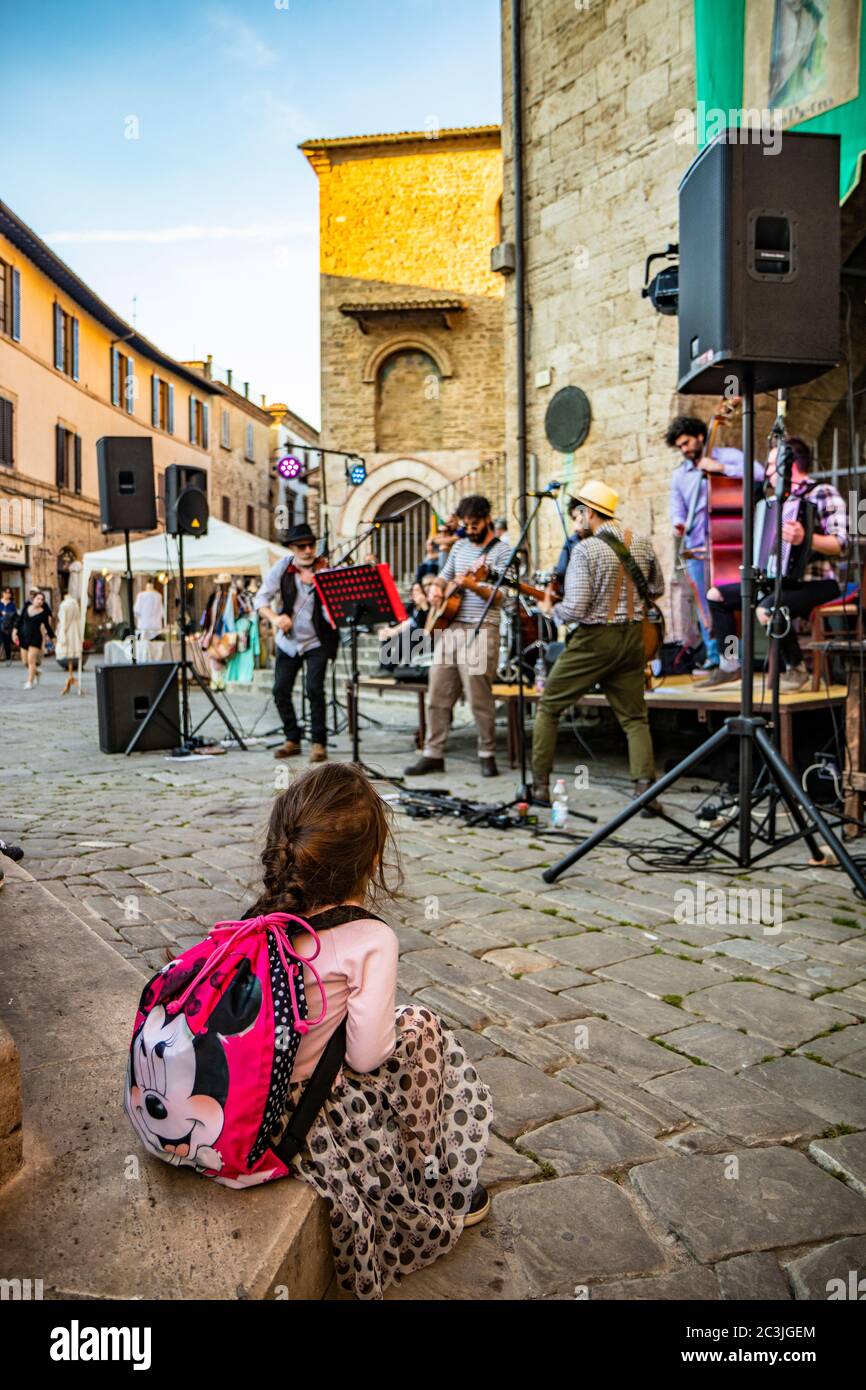 1. Juni 2019 - Bevagna, Perugia, Umbrien, Italien. Ein kleines Mädchen mit einem Zopf, bewundernswert, das eine Bandshow ansieht. Konzert von Straßenkünstlern während eines Amboss Stockfoto