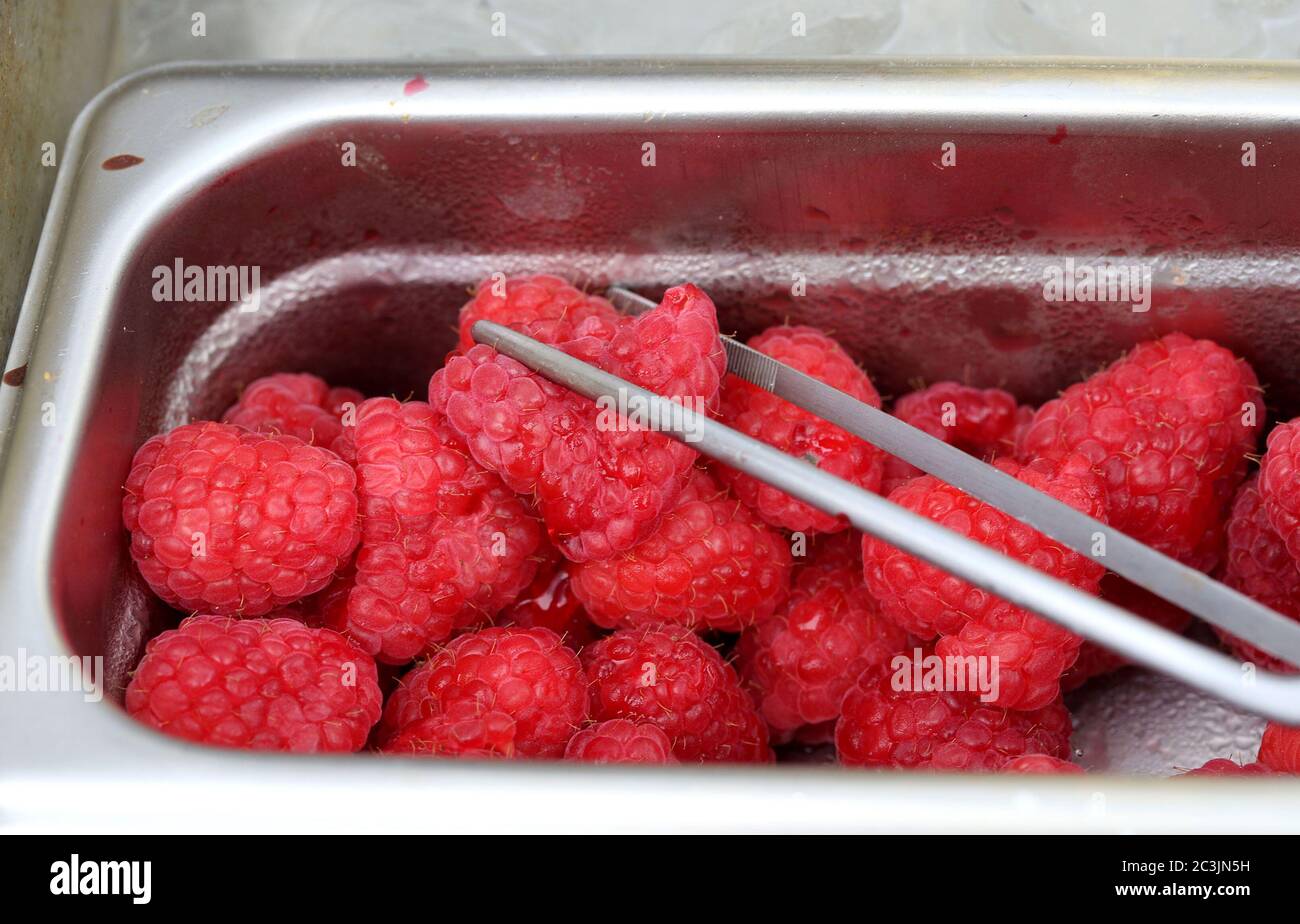 Rohe Himbeeren in einem Behälter mit Zange Stockfoto
