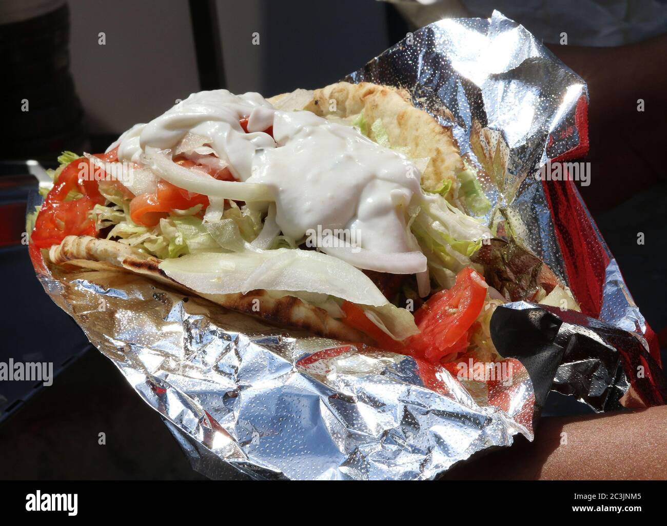 Ein Gyro-Sandwich gefüllt mit Lamm, Tomaten, weißen Zwiebeln, Salat und Zatziki-Sauce auf Pita-Brot Stockfoto