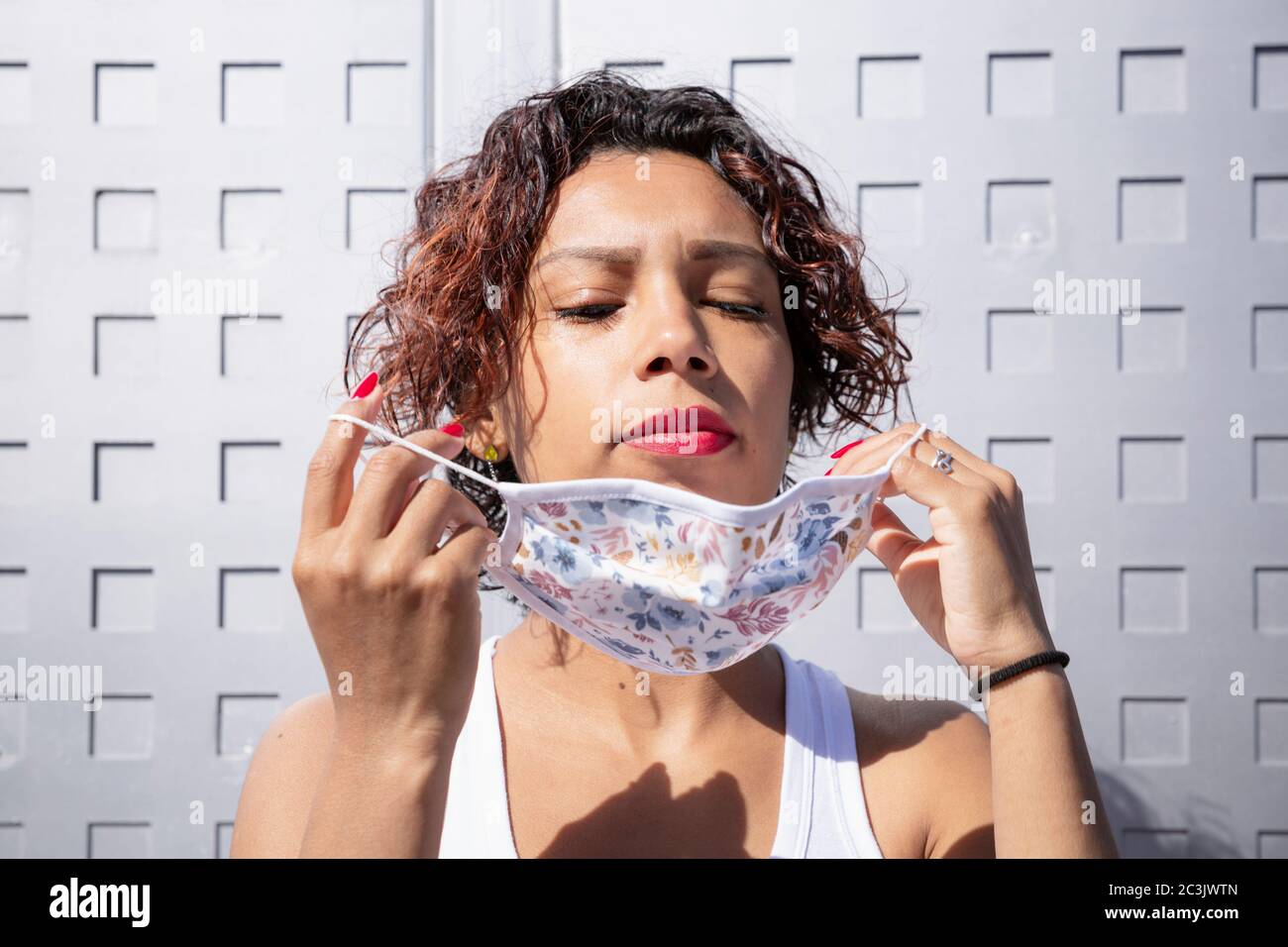 Attraktive lateinamerikanische Frau, die auf einer Gesichtsmaske auf der Straße. Konzept der neuen Normalität und der sozialen Distanzierung. Stockfoto