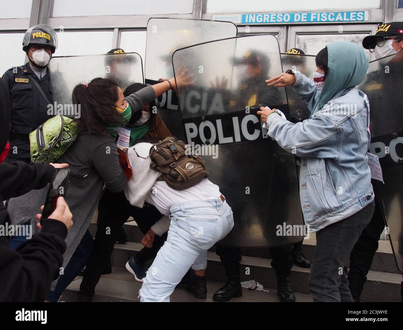 Frauen, die von der Polizei geschlagen wurden, als feministische Demonstranten, die Masken benutzen, wegen Covid-19, ein Sit-in vor der Staatsanwaltschaft´s Lima organisieren, um gegen Geschlechtergewalt und Feminizide zu protestieren Stockfoto