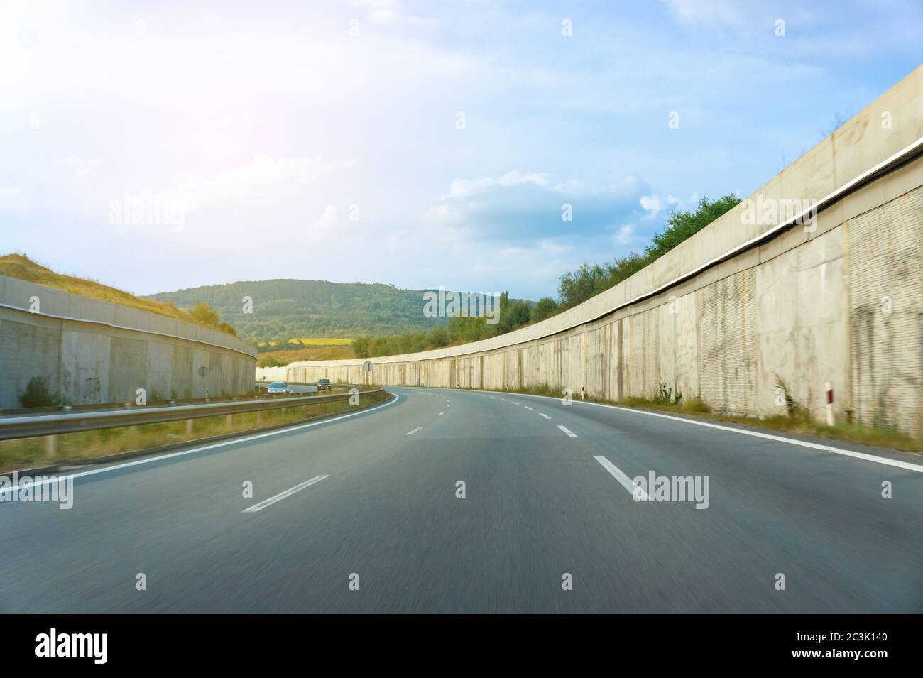 Asphaltstraße, die sich in die Ferne erstreckt, umgeben von Betonwänden. Straße in Bewegung Stockfoto