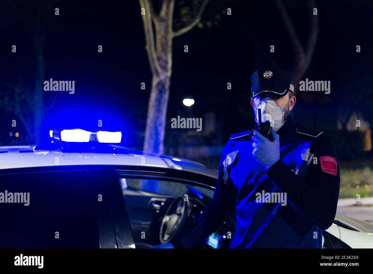 Nahaufnahme des Polizisten mit medizinischer Gesichtsmaske und Handschuhe sprechen mit Walkie-Talkie Radio-Set Stockfoto