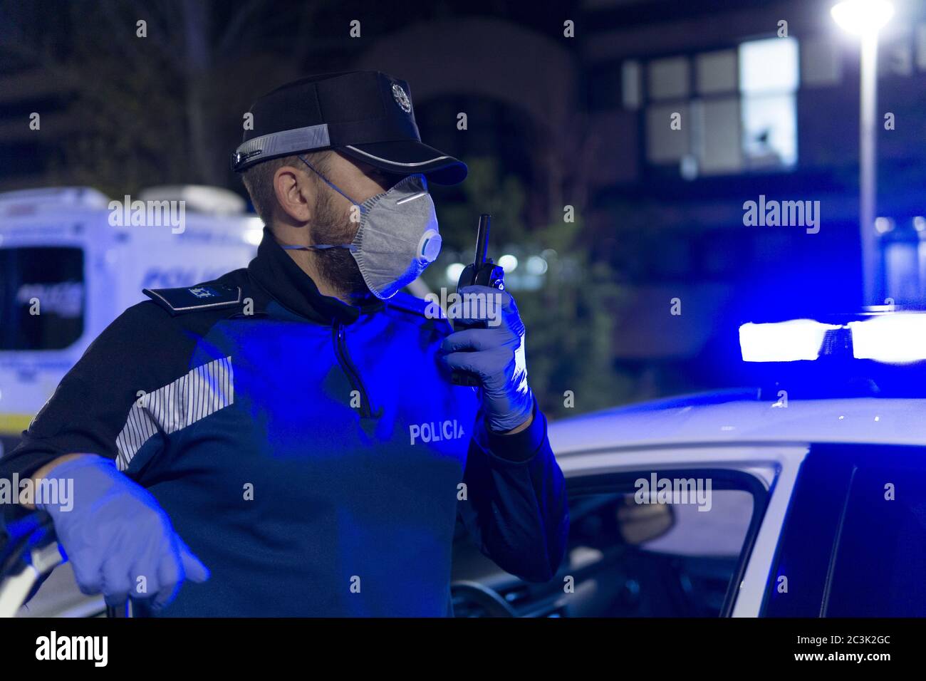 Nahaufnahme des Polizisten mit medizinischer Gesichtsmaske und Handschuhe sprechen mit Walkie-Talkie Radio-Set Stockfoto