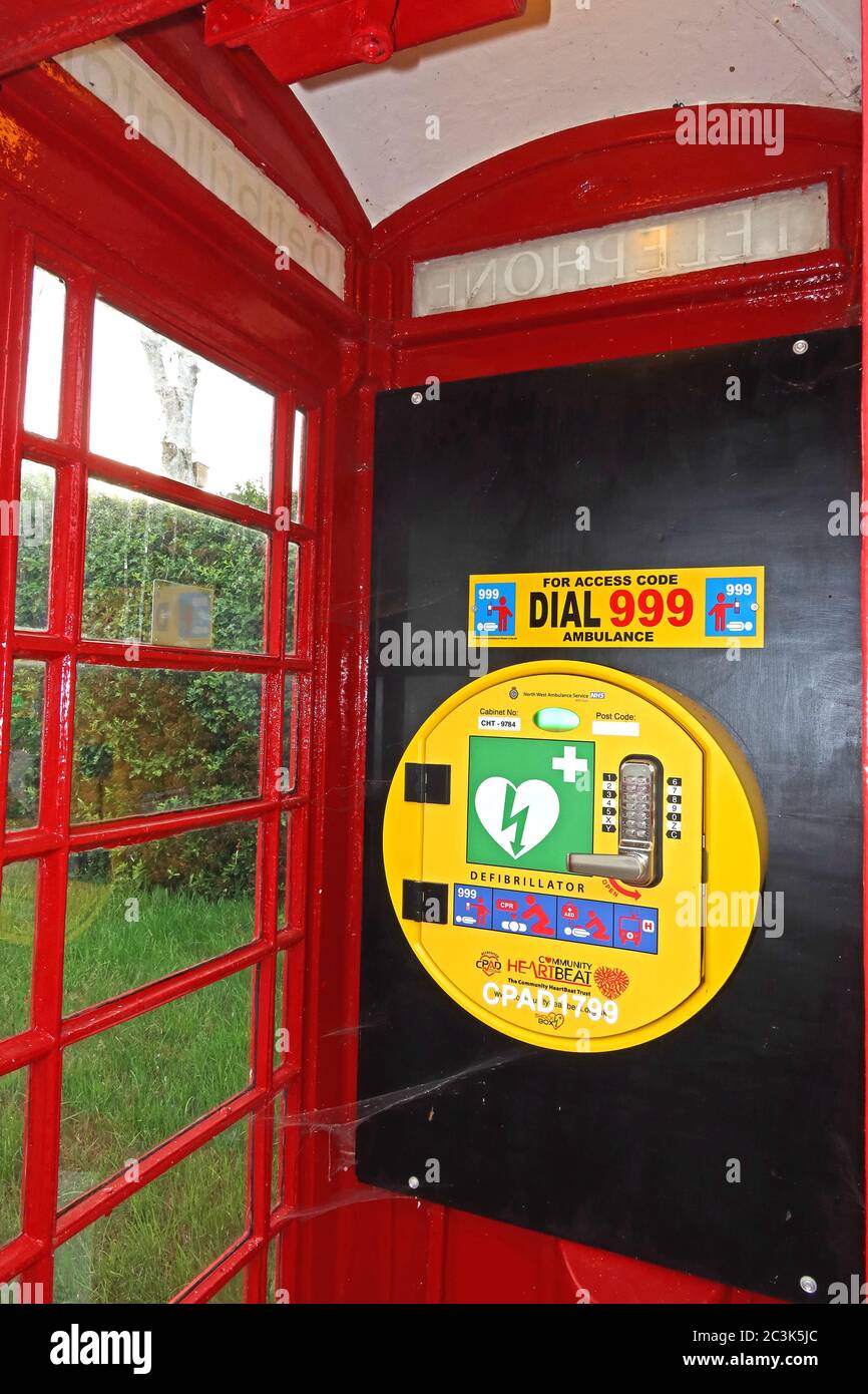 Defibrillator in roter britischer Telefonbox, Marbury Village, Cheshire, England, Großbritannien, AED, erste Hilfe für Herz - lebensrettend Stockfoto