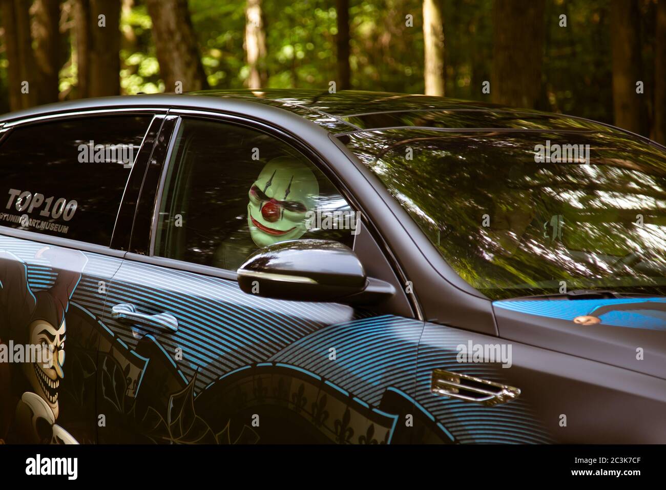 Moskau, Russland - 13. Juli 2019: Verrückter Clown in einem getunten Auto im Wald. Stockfoto