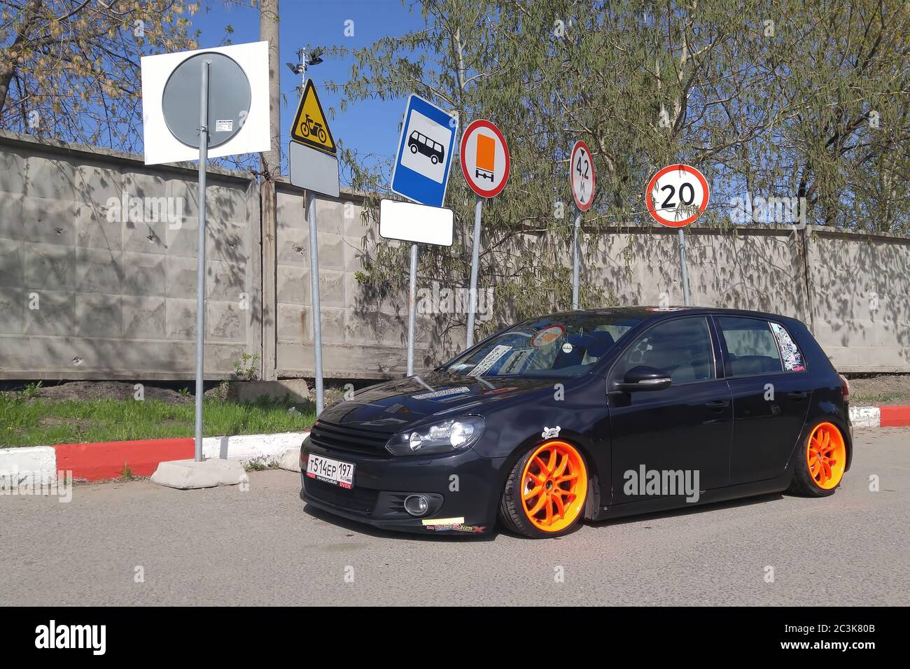 Moskau. Herbst 2018. Schwarz Volkswagen Golf mk 6 getunt von Luftfederung. Niedriges Auto mit breiten orangefarbenen Rädern, das unter verschiedenen Verkehrsschildern abgestellt wird. Stockfoto