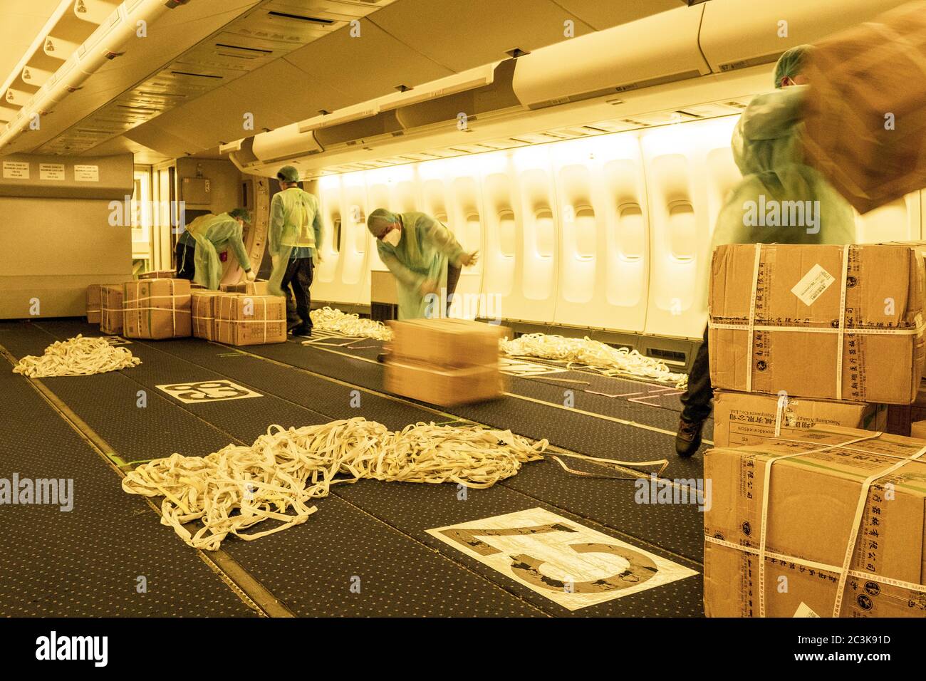 Chinesische Lader tragen Hazmat Anzüge Laden eines umgebauten Fahrgastes in Frachtschiff Flugzeug mit chirurgischen Masken und Kleider zu kämpfen COVID-Pandemie Stockfoto