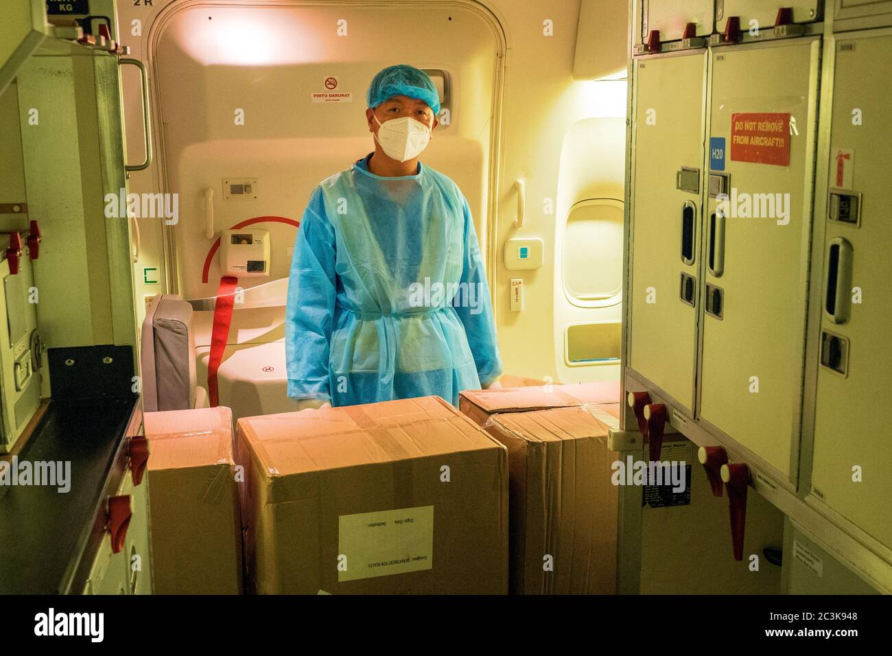 Chinesische Lader tragen Hazmat Anzüge Verladen eines konvertierten Beifahrer in Frachtschiff Flugzeug mit chirurgischen Masken und Kleider zu kämpfen COVID-Pandemie Stockfoto