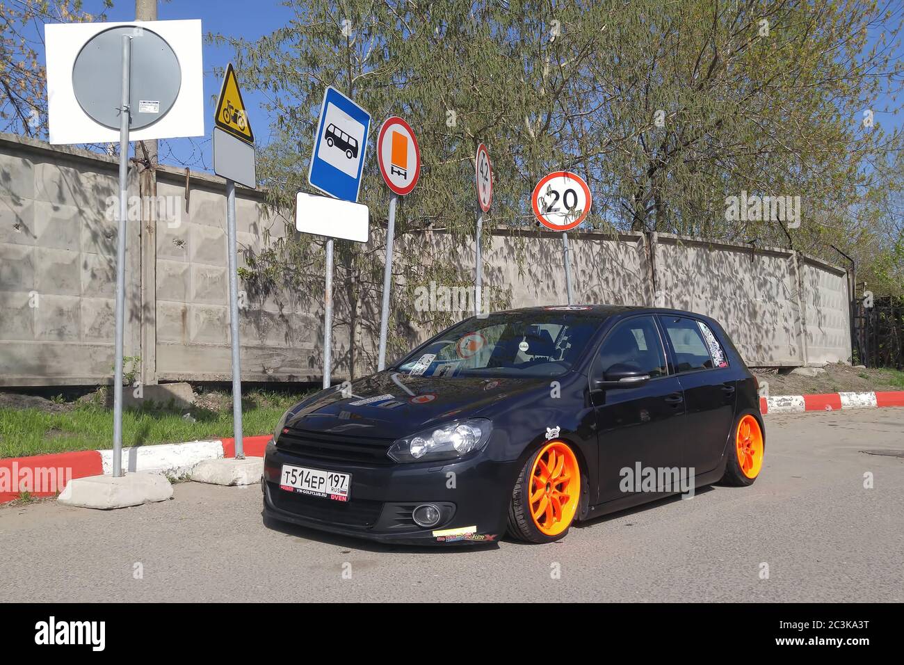 Moskau. Herbst 2018. Schwarz Volkswagen Golf mk 6 getunt von Luftfederung. Niedriges Auto mit breiten orangefarbenen Rädern, das unter verschiedenen Verkehrsschildern abgestellt wird. Stockfoto