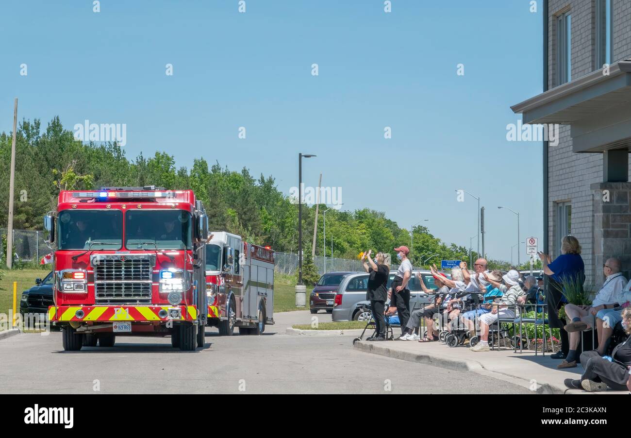 Die Fahrzeuge der örtlichen Feuerwehr ziehen an Bewohnern einer Altersresidenz vorbei, um während der Pandemie covid-19 ihre Stimmung zu erhöhen. Stockfoto