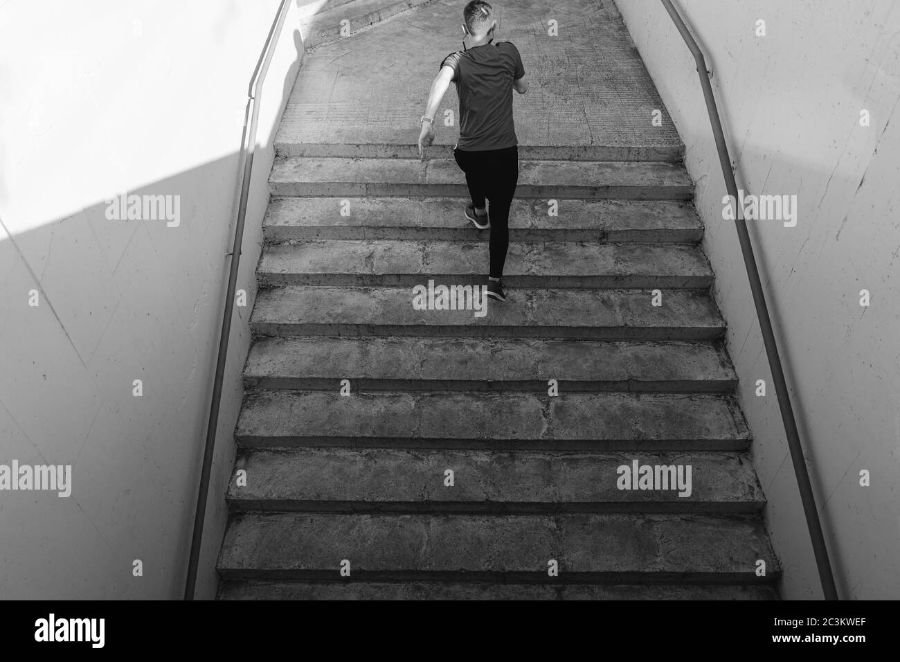 Junger Mann, der auf der Treppe der Stadt nach oben läuft. Fitness, Sport, Menschen, Sport und Lifestyle Konzept, Schwarz und Weiß Stockfoto