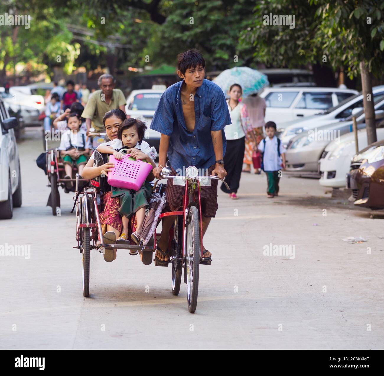 YANGON, MYANMAR - 13. NOVEMBER 2014: Kinder werden mit dem Fahrradkol in die Schule gebracht. Der Cyclo ist ein wichtiges Transportmittel in der Hauptstadt von Myanmar Stockfoto