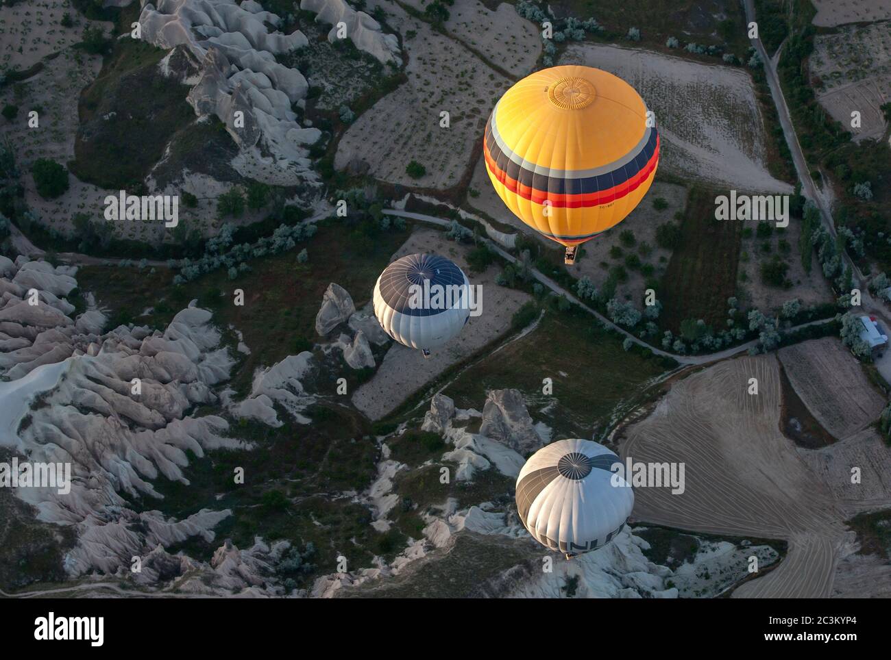 Eine Gruppe von Heißluftballons, die mit Touristen beladen sind, schweben über der unglaublichen Landschaft nahe der Stadt Goreme in der Region Kappadokien in der Türkei. Stockfoto