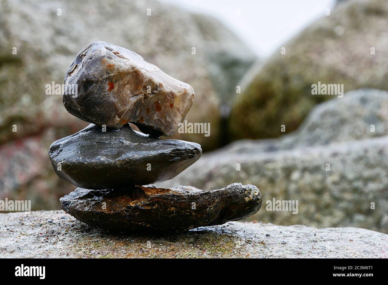 Die Kunst des Balancierens von Steinen, gestapelt auf einem großen Stein am Strand. Stockfoto