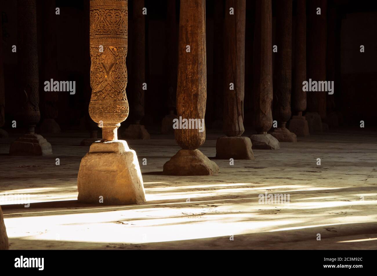 Schöne Holzsäulen mit eleganten Schnitzereien und dem Lichtstrahl in der alten Juma Moschee, Chiwa, Usbekistan Stockfoto