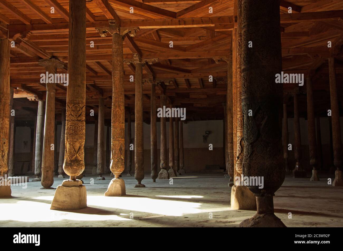 Schöne Holzsäulen mit eleganten Schnitzereien und dem Lichtstrahl in der alten Juma Moschee, Chiwa, Usbekistan Stockfoto