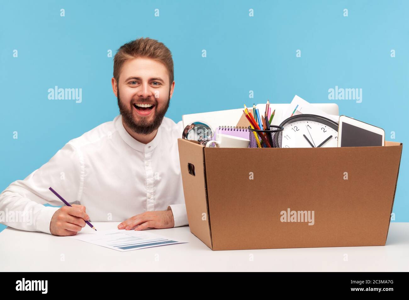 Glücklicher Mann am Arbeitsplatz mit Box von Habseligkeiten und lächeln an der Kamera, Gefühl aufgeregt durch die Gelegenheit der neuen Job, Beförderung und motiviert Stockfoto
