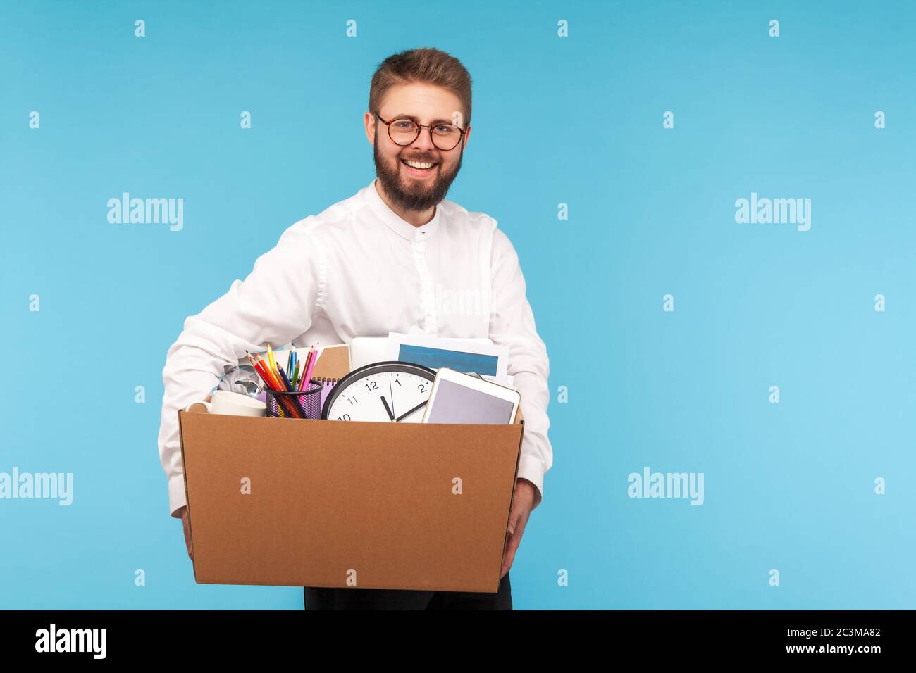 Glücklicher Mitarbeiter, der Box mit Sachen und lächelt an der Kamera, Umzug in ein neues Büro, Gefühl begeistert durch neue Arbeit, Beförderung und Karriere succ motiviert Stockfoto