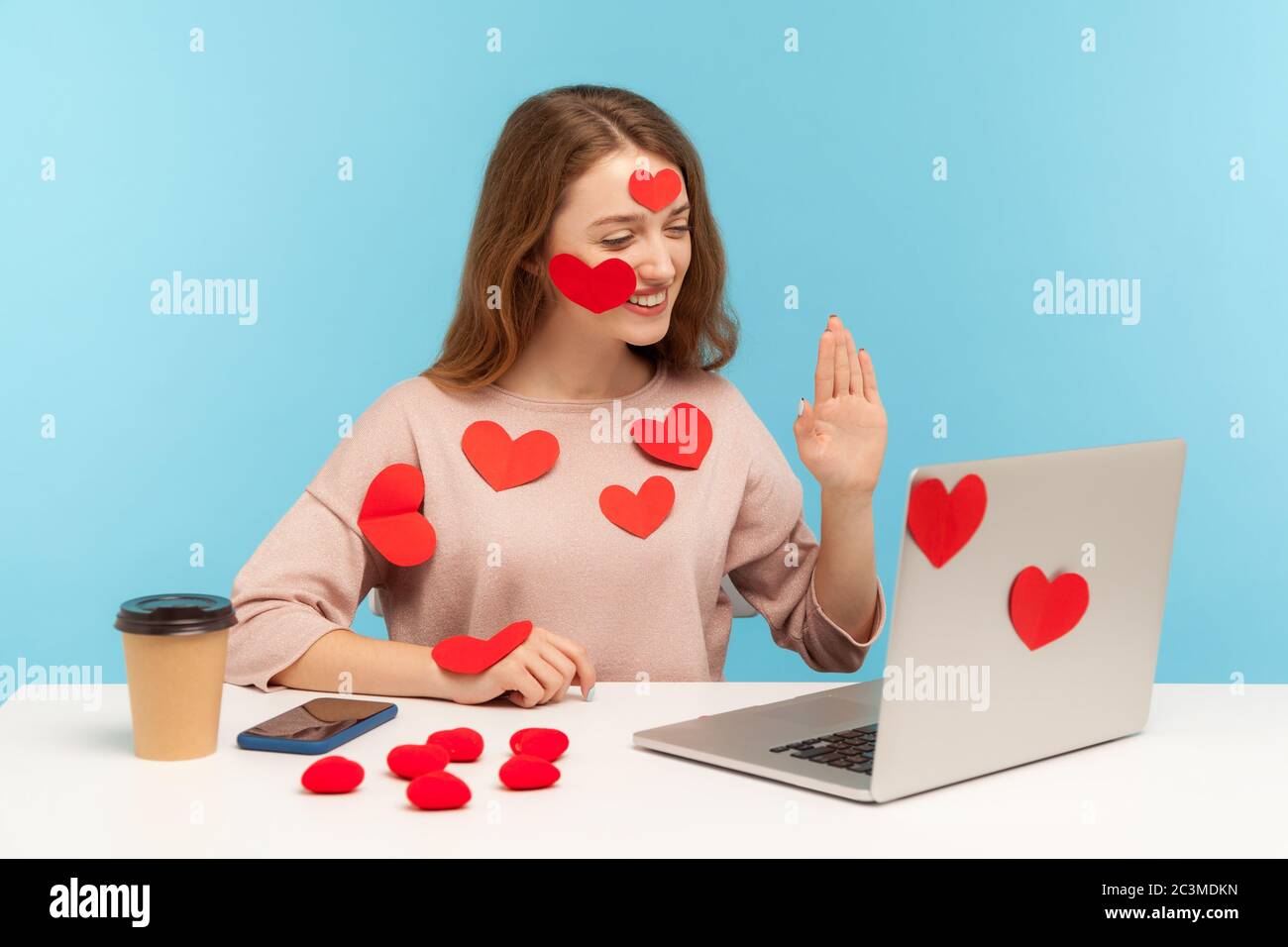 Erstaunlich freundliche Frau mit freundlichen Ausdruck sitzen alle mit Aufkleber Liebe Herzen bedeckt und gestikuling hallo sprechen auf Video-Anruf, romantische Beziehungen Stockfoto