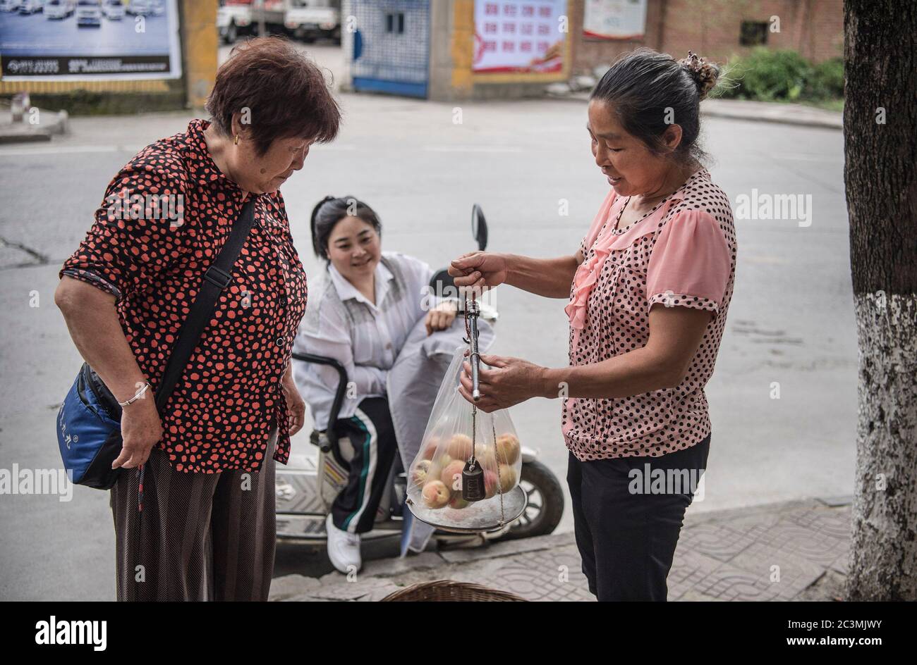 (200621) -- ANKANG, 21. Juni 2020 (Xinhua) -- Li Zengyis Frau Tang Guoqun (1. R) und ihre Tochter Li Dan (C) verkaufen Pfirsiche auf einem Markt in Ankang, nordwestlich der chinesischen Provinz Shaanxi, 19. Juni 2020. Um die Armut zu überwinden, verlegte Li Zengyi, ein Dorfbewohner im Dorf Wenhua der Stadt Ankang, 1997 seine Familie, einschließlich seiner siebenjährigen behinderten Tochter, in ein provisorisch geführtes Haus auf einem Berg, um Pfirsiche zu kultivieren. Li Wei, der ältere Sohn von Li Zengyi, ging nach dem Abschluss der Mittelschule zur Arbeit in der südchinesischen Provinz Guangdong, um die Familie zu unterstützen. Li Peng, der jüngere Sohn, Stockfoto